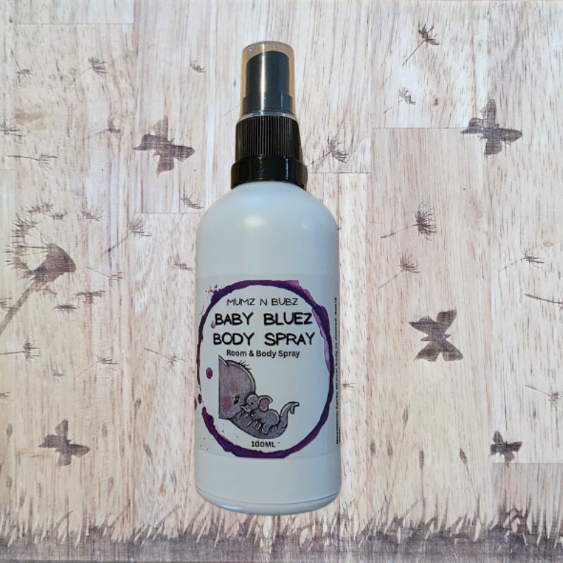 Baby Bluez body spray bottle on a wooden background with butterfly and dandelion designs.